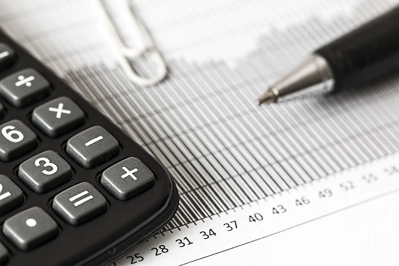 A calculator and pen resting on a printed bar chart