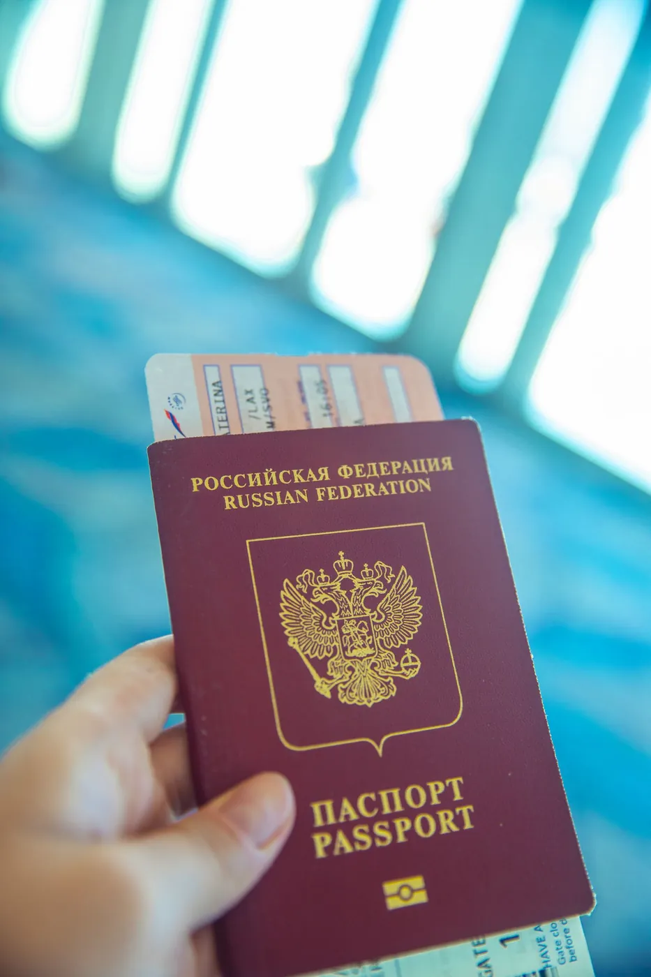 A hand holding a passport and a boarding pass
