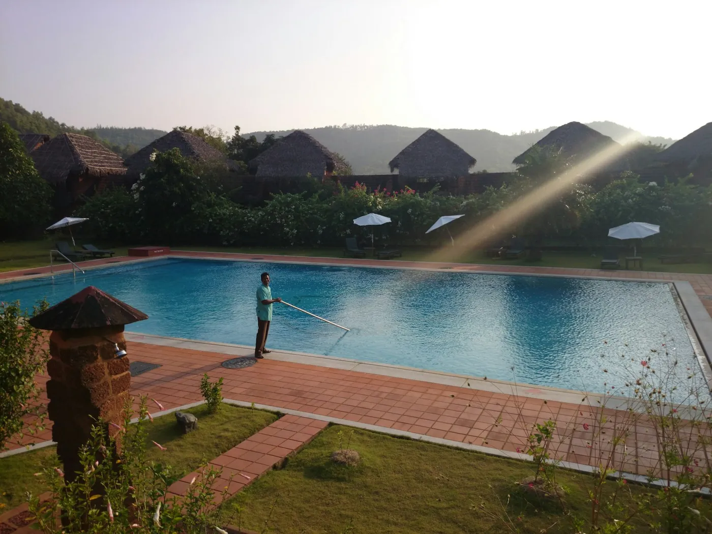 A worker cleaning a villa pool, part of the daily upkeep that protects a five-star guest experience