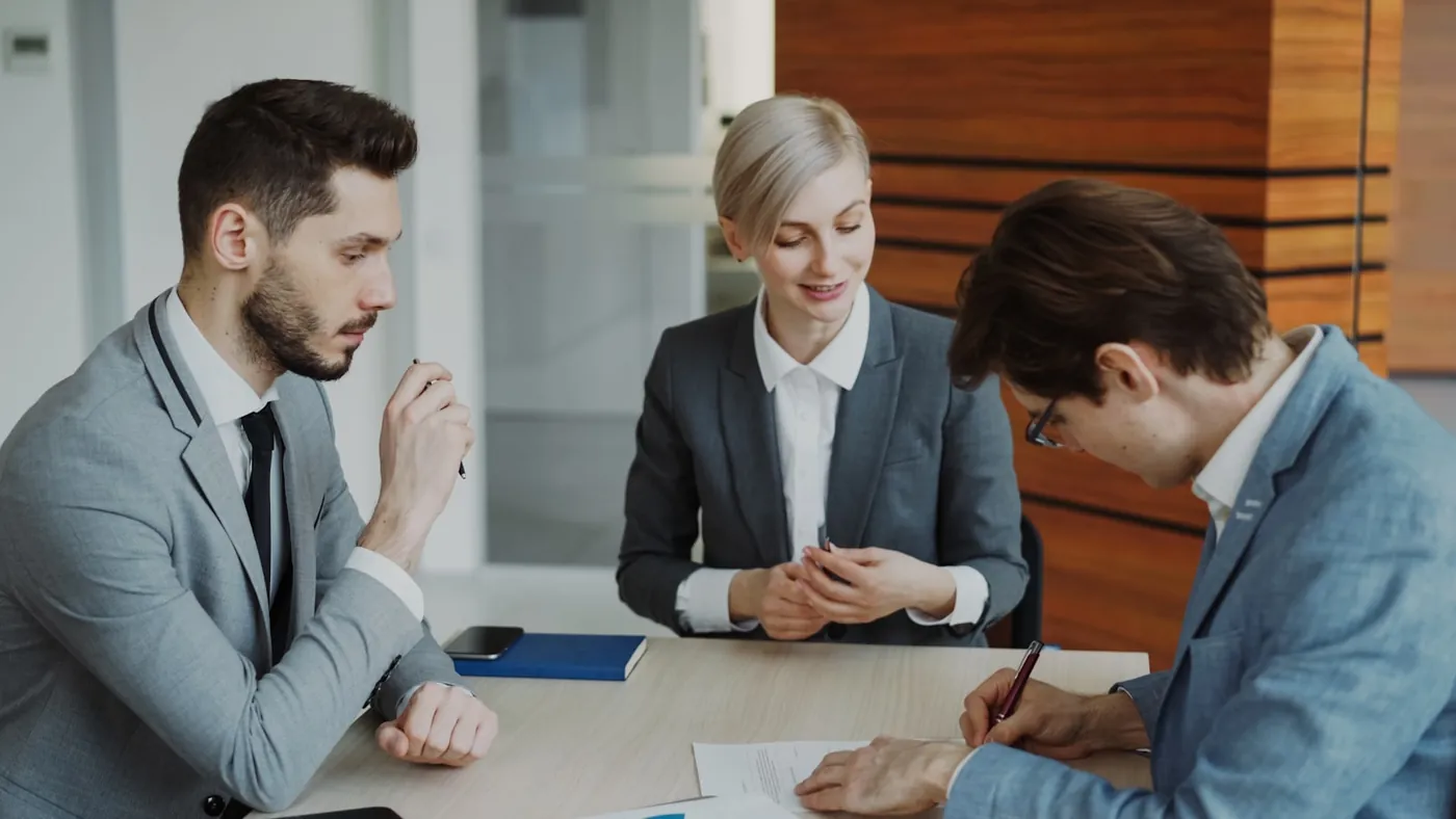 Two people signing a property contract across a table